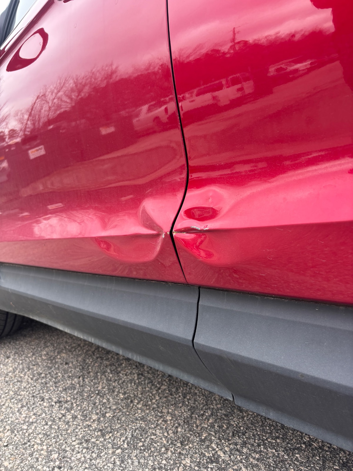 Red vehicle door dent before repair